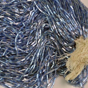 These Bugle Beads Light Blue Iridescent come in a 17.5 ounce package. They are 4mm long and 2mm wide. The very narrow diameter allows more detail to be put into your designs.