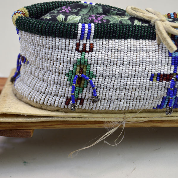 Pictured here is the rawhide platform. Cheyenne-style toy cradle, crafted with a rawhide platform and fully adorned in 13/0 cut seed beads, each detail secured with sinew stitching to reflect traditional artistry in miniature form