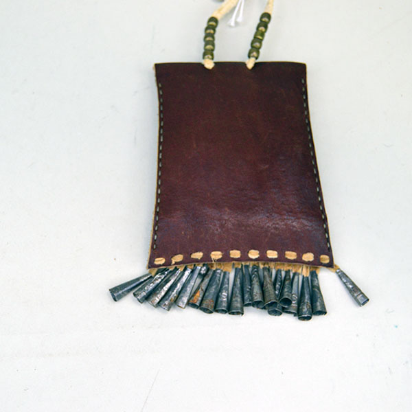 This Strike-a-Lite bag features periwinkle seed beads in a hand-stitched Tipi design, paired with a saddle-colored leather strap; pictured here is the back, showcasing the detailed stitching and traditional layout.