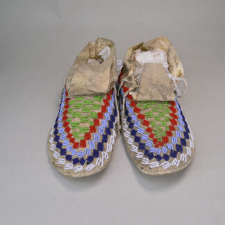 These antique Northern Plains-style moccasins feature a distinctive checkerboard beadwork pattern. Soft braintan leather, rawhide soles. One of a Kind.