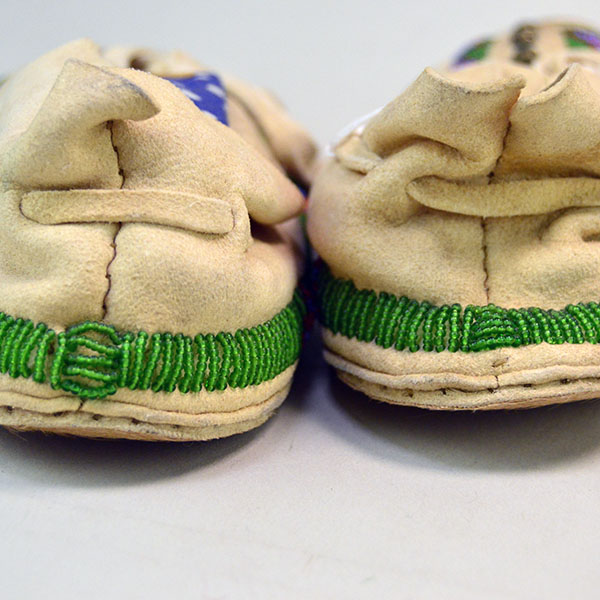 Pictured here is the beadwork on the heel of these Northern Plains-style child’s moccasins, where vibrant designs are stitched into supple deerskin above rawhide soles with natural hair—highlighting tradition from every angle.