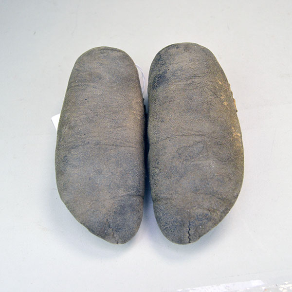 This image shows the bottom of vintage child’s moccasins in Cree style, made from brain-tanned deer hide and constructed with a traditional center seam.