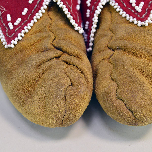 Pictured here is the center seam of Eastern Woodland-style moccasins, meticulously hand-sewn with sinew and fully lined in vibrant red wool, showcasing the traditional craftsmanship and structural integrity of the design.