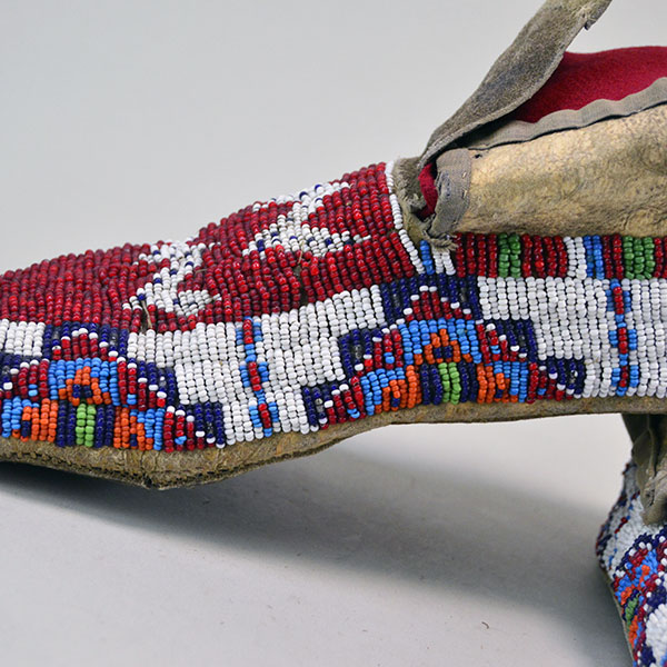 These antique moccasins, crafted in the Northern Plains style, feature braintanned deerskin leather stitched with real sinew, fully beaded uppers, and rawhide soles, beautifully showcasing the intricate beadwork.