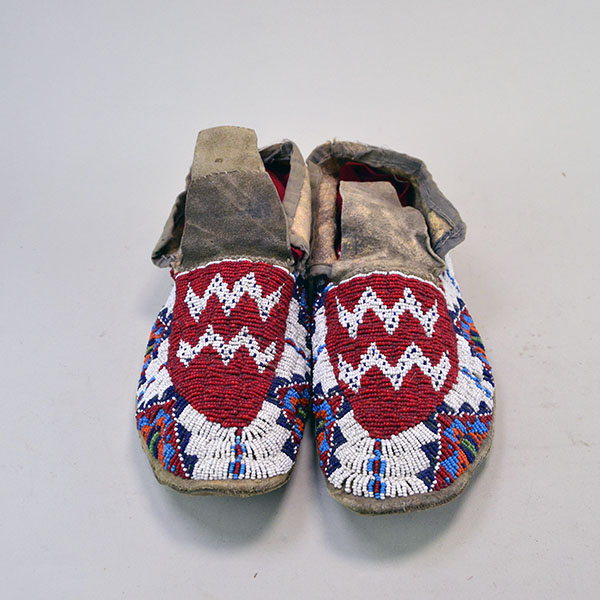 These antique moccasins, crafted in the Northern Plains style, feature braintanned deerskin leather stitched with real sinew, fully beaded uppers, and rawhide soles, beautifully showcasing the intricate beadwork.