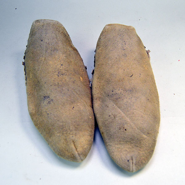 Pictured here are the soles of moccasins crafted from brain-tanned deer hide, featuring silk-embroidered vamps that highlight traditional artistry and fine material choice