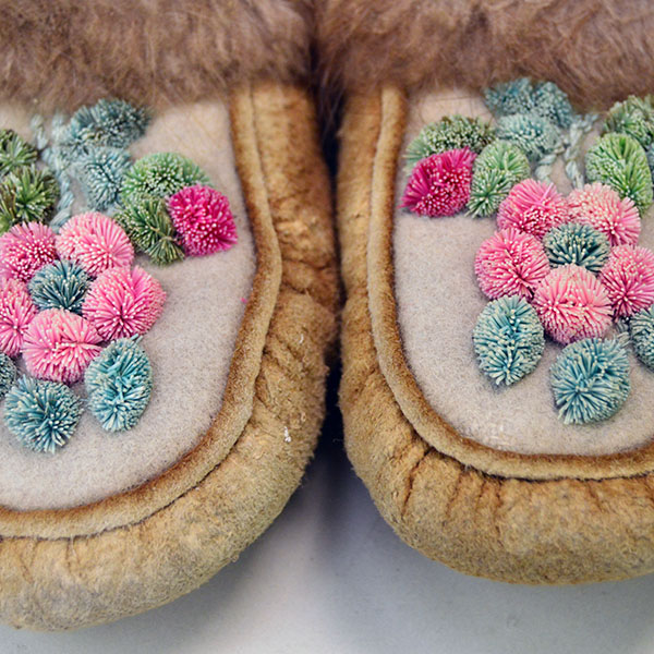 This top view showcases Cree-style youth moccasins crafted from moosehide leather, with a soft white wool vamp beautifully adorned by a delicate hair tufting design.