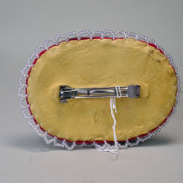 Back view of large beaded bird barrette on red velvet with deerskin backing.