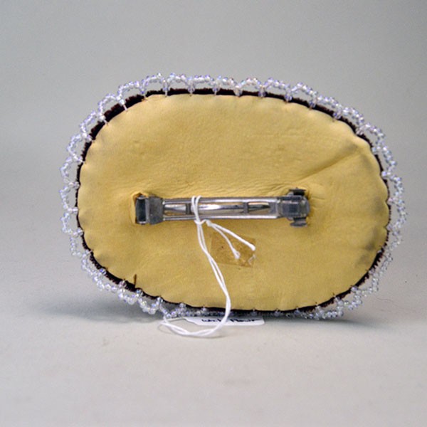 Back view of large beaded flower barrette on red velvet with deerskin backing.