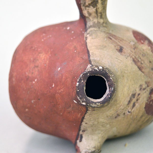 Top close up view of small canteen Acoma style decorated with floral design on one side and red on the other.