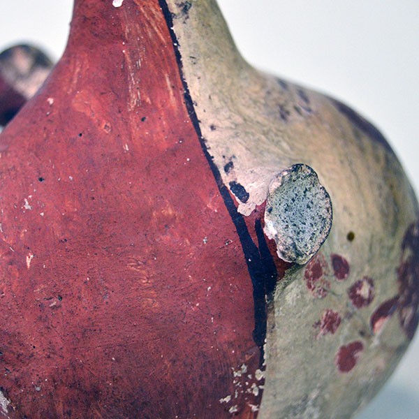 Side view of small canteen Acoma style decorated with floral design on one side and red on the other.