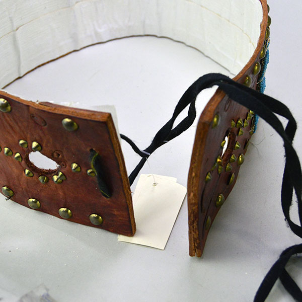 This vintage handcrafted belt, beaded in blue with a geometric design, is pictured here showing the white tape applied to the inside