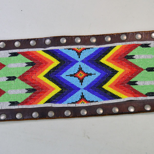 This belt features a beaded feather design crafted with 13/0 cut seed beads and accented by silver rivets