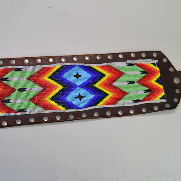 This belt features a beaded feather design crafted with 13/0 cut seed beads and accented by silver rivets
