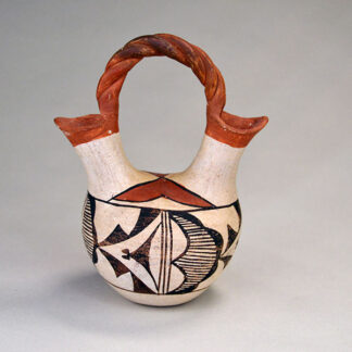 This small Wedding Vase- Acoma Style features a textured top handle. stands 5.5" tall. At its widest points it measures 4.5". One of a Kind.