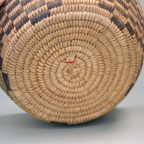 This beautiful handwoven Pima‑style basket features tightly coiled grass and yucca, with devil’s claw creating the dark designs. One of a Kind. Pictured here is the flat bottom.