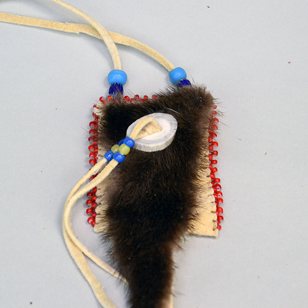 Neck Bag- Otter Fur Flap features beautifully soft smoke‑colored deerskin leather. edge‑beaded the sides with white‑center red seed beads. one of a kind. pictured here is the otter fur, the antler button, and the pony beads.