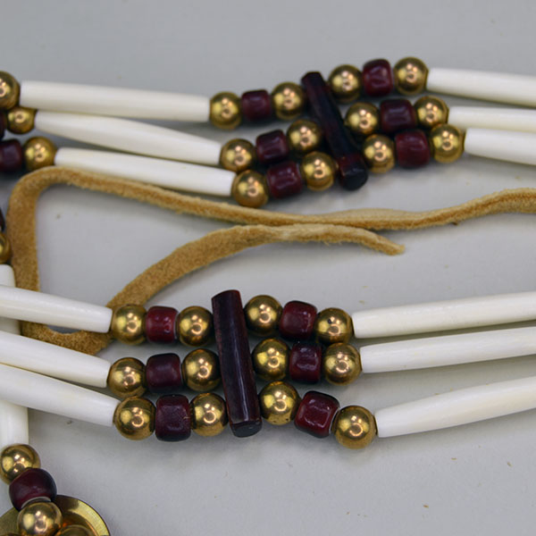 three‑row Choker- White Center Cranberry stands out with its striking mix of bone, brass, and deep cranberry‑colored crow beads. measures 16 inches long. pictured here is the spacers, the brass beads, the bone hairpipe and the crow beads.