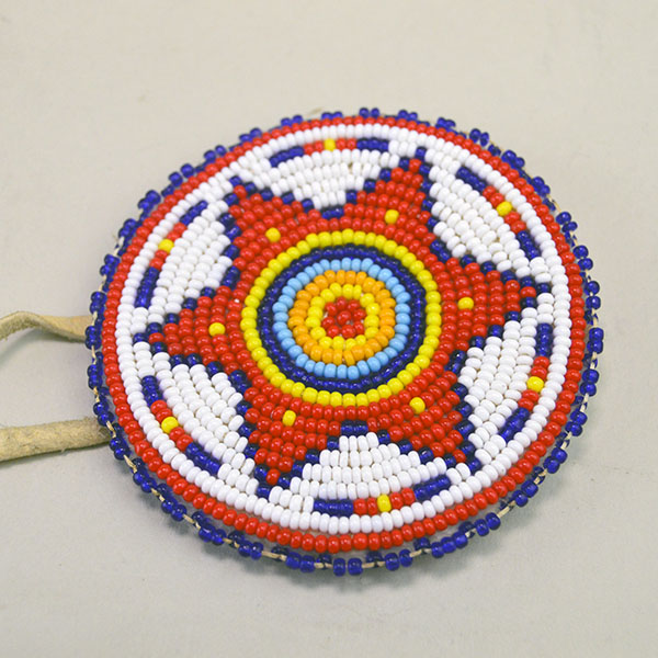 group lot offers a striking mix of accessories. beaded rosette star, bone cutout pendant, stamped brass Kokopelli, and stamped German silver concho. pictured here is the beaded rosette.