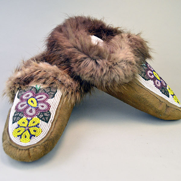 hand‑crafted Cree smoked‑moosehide moccasins showcase classic Cree styling. vibrant floral beadwork design adorns the vamp. beaver fur to the cuffs.