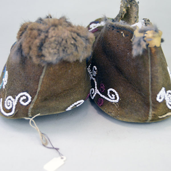 Antique Cree‑style moccasins showcase classic Cree design. Vibrant floral beadwork design, some bead loss. Fur to the cuffs, one missing. women's 8.5. The heals, also showing one fur cuff missing.