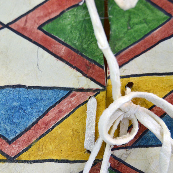 Add this brightly Parfleche- Painted Rawhide Container to your collection! The container measures approx. 11" wide x 15" long. One of a Kind. The closure ties.