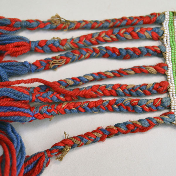 Sash- Antique Loom Beaded showcases a bold floral design. Approx. 24" partially braided wool‑yarn fringe. the sash reaches approx. 55" in total length. the braided frindge.
