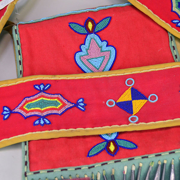 This Bag- Great Lakes Style showcases bold 11/0 seed bead floral and geometric designs. measures approx. 10" wide X 11" long, and the strap 28.5 " long. The different beaded designs on the bag and strap.