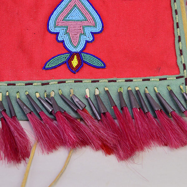 This Bag- Great Lakes Style showcases bold 11/0 seed bead floral and geometric designs. measures approx. 10" wide X 11" long, and the strap 28.5 " long. The red horse hair meta cones at the bottom of the bag.