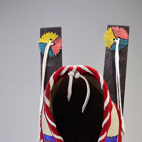 Cradleboard Parfleche features rawhide construction and a hand‑painted design. measures approximately 21 inches long, 7 inches wide at the head. The rawhide decorative design on the top part of the skies.