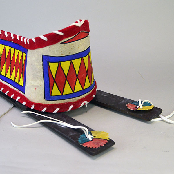 Cradleboard Parfleche features rawhide construction and a hand‑painted design. measures approximately 21 inches long, 7 inches wide at the head. The top of the head showing the design.