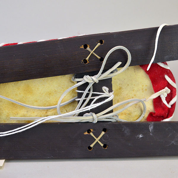 Cradleboard Parfleche features rawhide construction and a hand‑painted design. measures approximately 21 inches long, 7 inches wide at the head. another view How the skis and the cradleboard are attached with raw hide and deerskin leather lacing.