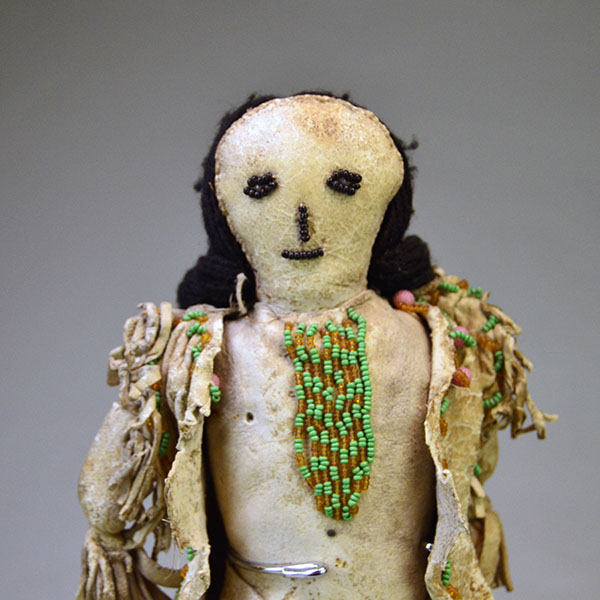 This antique Doll- Northern Plains Style offers exceptional handmade detail and strong visual presence. She stands approx. 14 inches tall. One of a Kind. The beaded face and the beaded design on the dress.