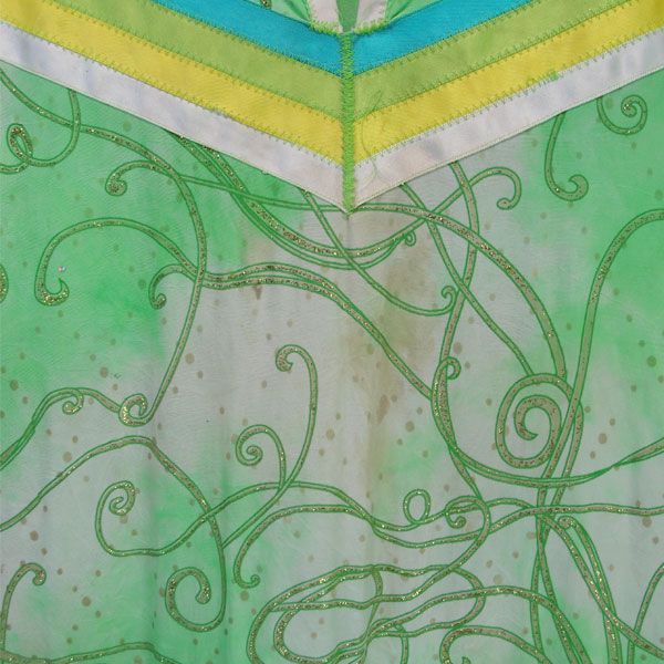 Child’s Jingle Dress, This Child’s Jingle Dress features a green and white top fabric decorated with sequins and glitter designs. Child’s Size Medium/Large. The front showing the stain.