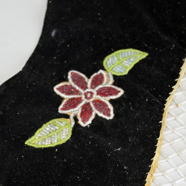 This floral beaded cape dates from the 1950s to 1960s and features an elaborate net fringe. few beads are missing, consistent with age and use. the floral beading on the black velvet.
