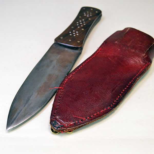 Knife- Beaver Tail Style with Decorative Brass‑Pinned Handle and Reinforced Leather Sheath. Approx. 7" double-edged Blade, and 5" handle . One of a Kind. The back of the leather sheath, and the double-edge knife.