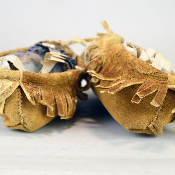Moccasin- Child Center Seam, brick‑stitched the vamp in white, mustard yellow, and red‑orange. Like new , never worn, estimated child’s size 8–9. The heal of the moccasins.