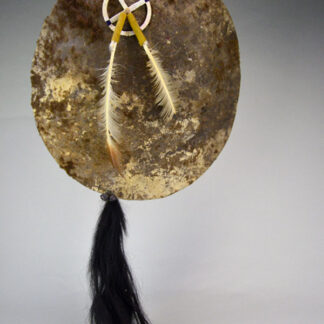 Striking shield features a 15″ buffalo‑rawhide body, quilled medicine wheel, Two old turkey feathers, a hose tail. One of a Kind.
