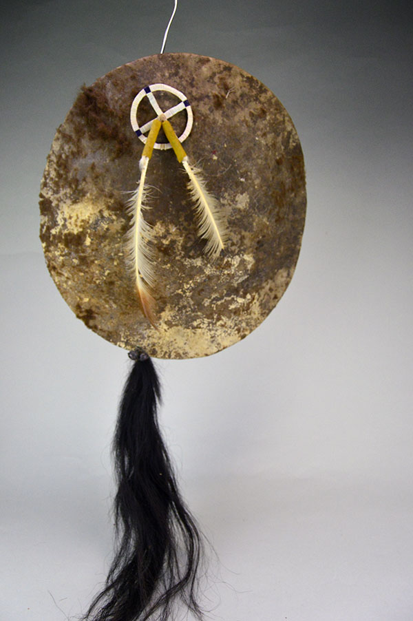 Striking shield features a 15″ buffalo‑rawhide body, quilled medicine wheel, Two old turkey feathers, a hose tail. One of a Kind.