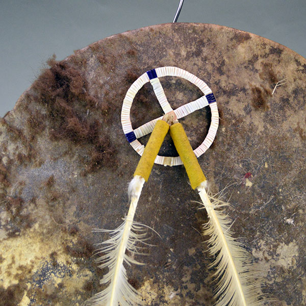 Striking shield features a 15″ buffalo‑rawhide body, quilled medicine wheel, Two old turkey feathers, a hose tail. One of a Kind. The quilled medicine wheel and turkey feathers.