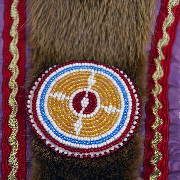 Turban Crafted in Otter Fur features six rosettes measuring between 1.25" x 2.5". approx. 21.5 inches inside circumference, drop measures about 24 inch". The rossette and the colors against the light brown of the otter fur.