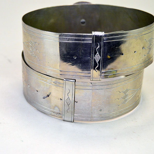Handmade nickel silver armbands with stamped lines and diamond motifs; adjustable slide clips; approx. 1.25" wide x 14" long. One of a Kind. The back of the armbands showing the slide closure.