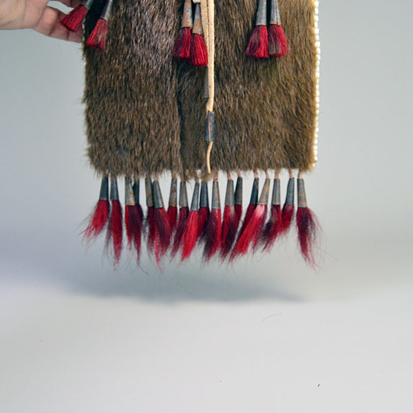 Bag- Quilled Thunderbird Motif with Braintanned leather, otter fur, deer‑hair drops, and antique white pony beads. Measures approx. 14.5" × 6". the otter fur on the bottom under the quill work and the red hair deer cone drops on the bottom.