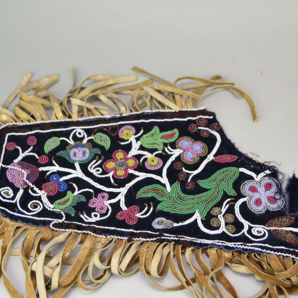 Antique Cree‑style floral beaded jacket shoulder panel with Braintanned fringe, black velvet, bead loss, and ribbon wear; measures 26 inches long. Showing that the beadwork around the brow ribbon coming apart.