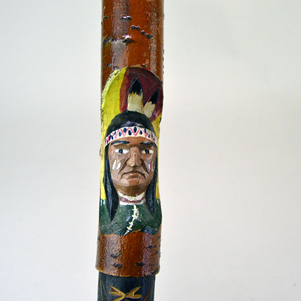 Vintage birch Cane- Indian Head & Leaves, approx. 36" long and 1.5" wide, featuring a hand‑chipped portrait, chipped leaf designs, hand‑painted details. the painted Indian head against the birch bark.