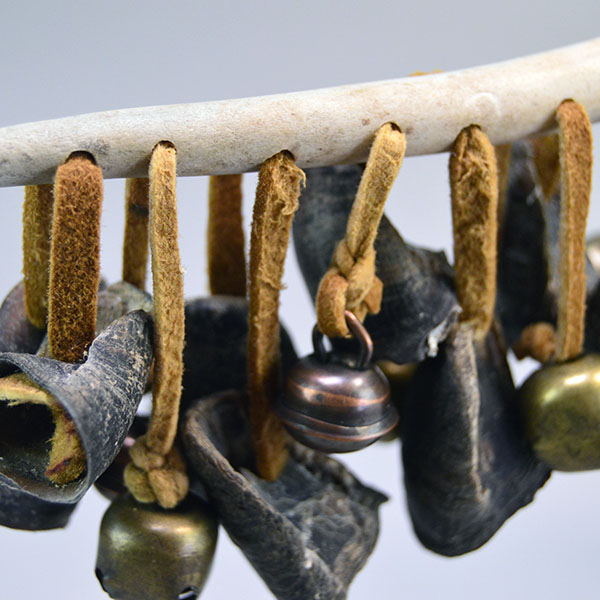 Dance Rattle- Deer Toes with 10 deer toes, 8 bells, 10″ bone handle, Braintanned leather lacing and wrist strap; handcrafted for dance or display. The tiny bells and deer toes on the Braintanned leather lacing.