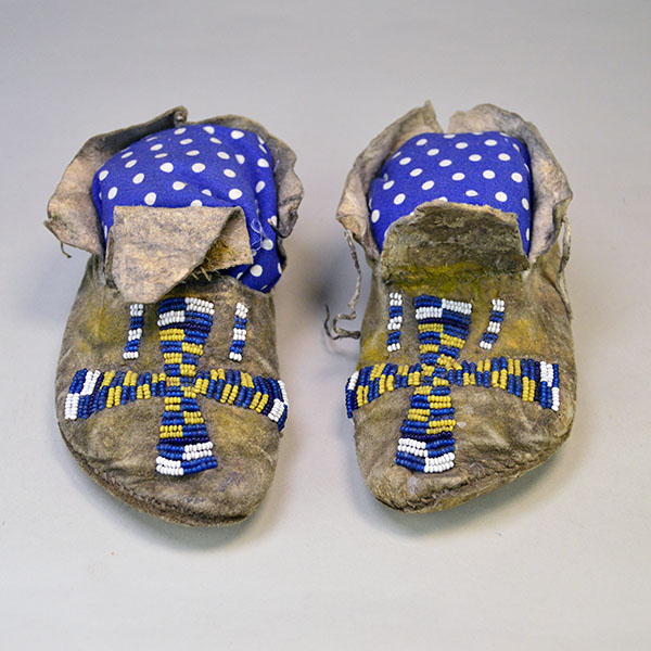 Antique Moccasins- Arapaho Style Child's with a bold cross design, intact 11/0 beadwork, Braintanned hide, rawhide sole, and early 1900s craftsmanship. Pictured here is the front view of these moccasins.