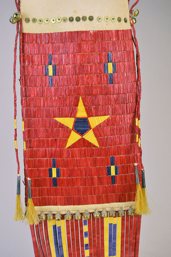 Pipe Bag- Double-sided Quillwork, Braintanned deerskin, braided fringe, cone‑drop tassels, and brass bells. Measures 45" with light age wear. the front quill work design and the quilled tassels on the sides of the bag.