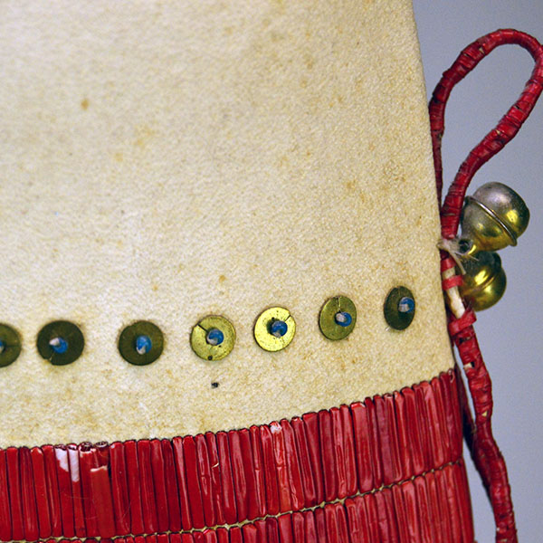 Pipe Bag- Double-sided Quillwork, Braintanned deerskin, braided fringe, cone‑drop tassels, and brass bells. Measures 45" with light age wear. The sequences on the top of the bag.