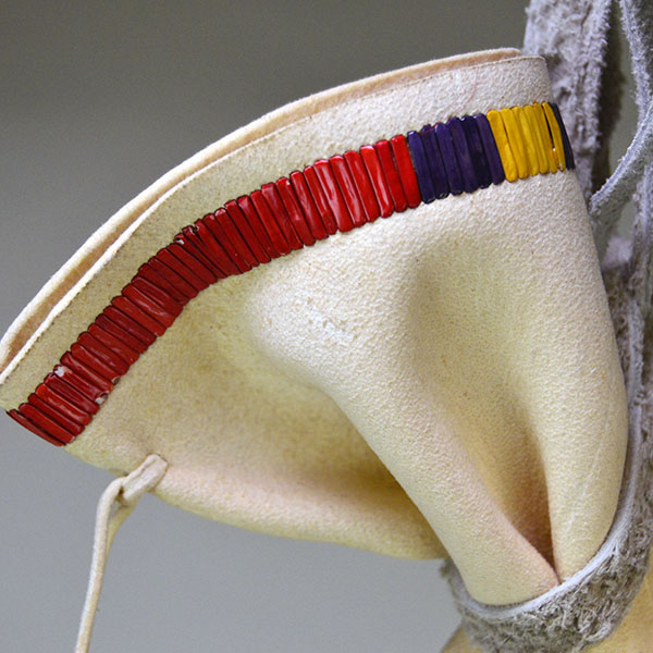 Pipe Bag- Double-sided Quillwork, Braintanned deerskin, braided fringe, cone‑drop tassels, and brass bells. Measures 45" with light age wear. The top of the bag.